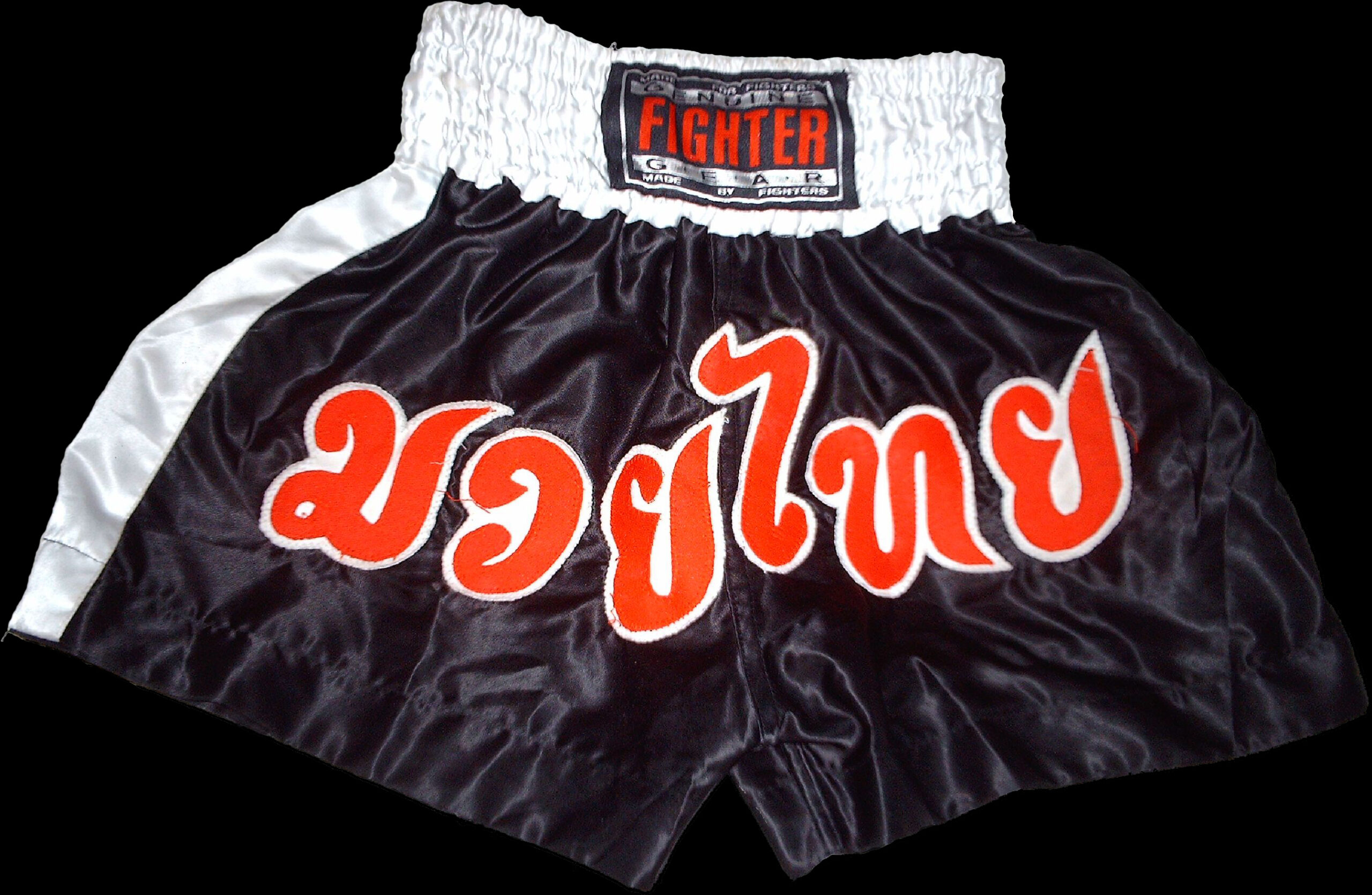 Black and white Muay Thai shorts with large red Thai lettering across the front